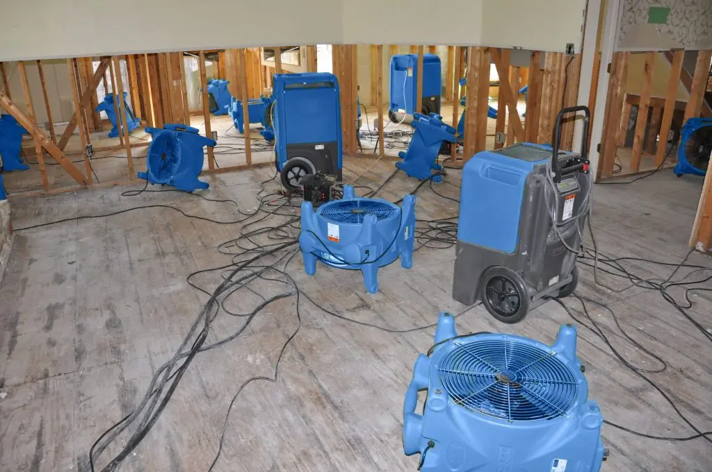 Air movers drying a gutted Pittsburgh room after major water damage
